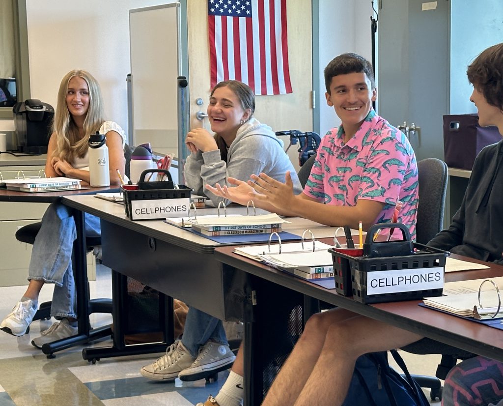 Students are pictured sitting at a table in a classroom at the HFM BOCES Career and Technical Education Center. The students are smiling while engaging in conversation