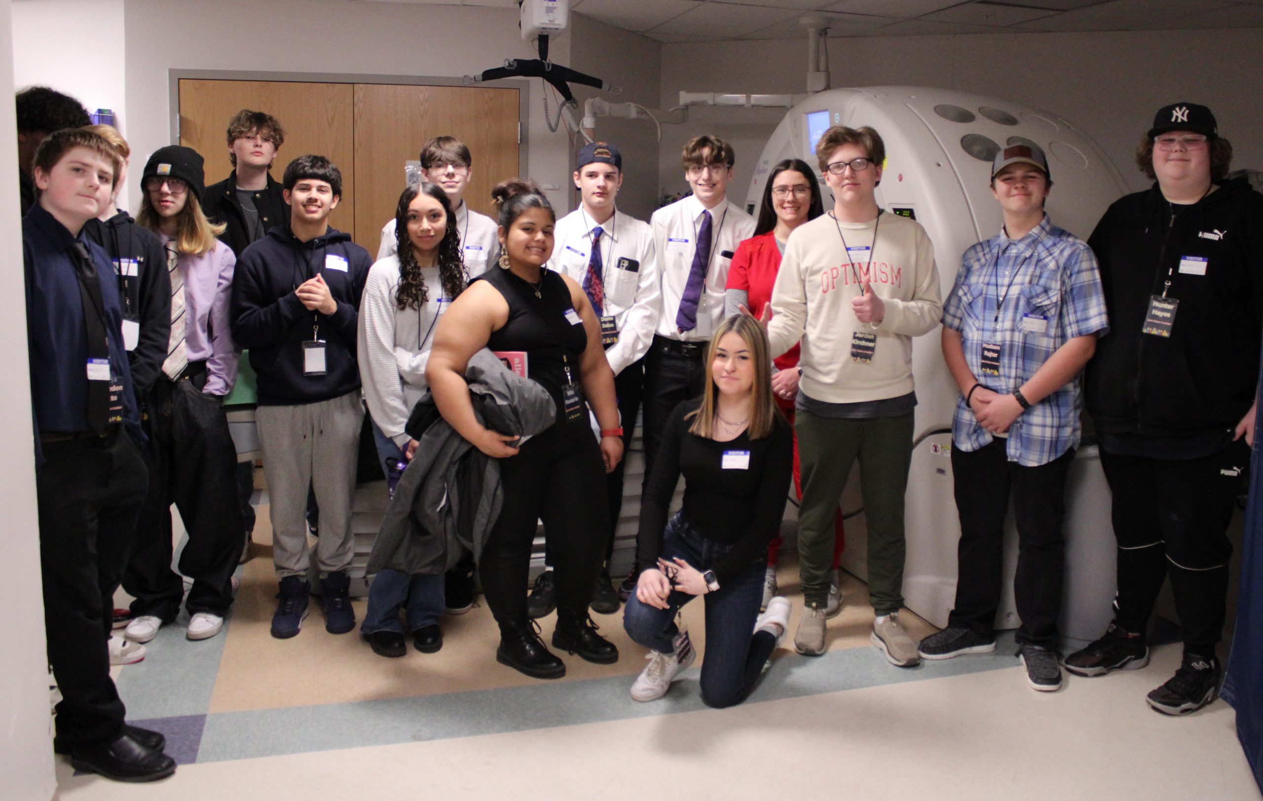 A large group of PTECH students are pose for a photo while on a workplace tour of St. Mary's Healthcare. Seen in the photo is PTECH completer Hannah Ryder (wearing red work scrubs) who spoke to the students herself.